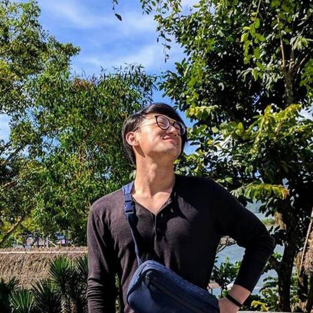 Sean Wu posing in a park surrounded by trees.